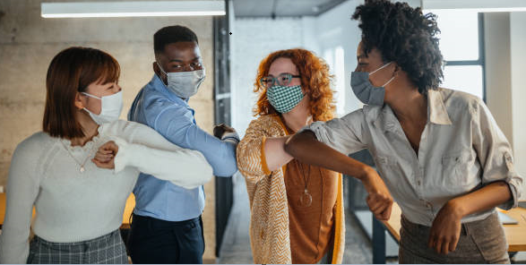 Four diverse people wearing masks in a circle and bumping elbows