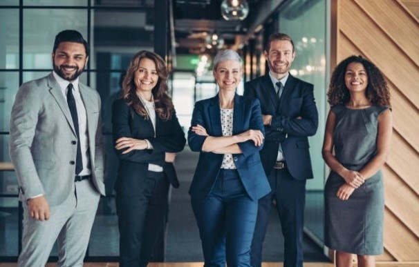 Five diverse people in suits, arms crossed, smiling and facing the camera