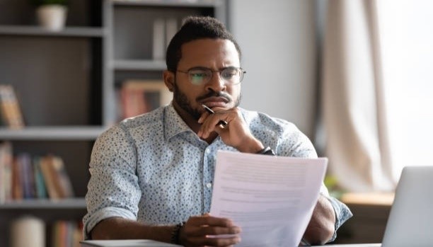 Man with glasses studying a piece of paper