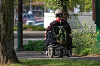 Photo of a person in a wheel chair on the sidewalk