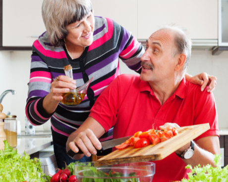 Person writing on a paper at a table with a pen; glasses and a coffee cup are in the background.