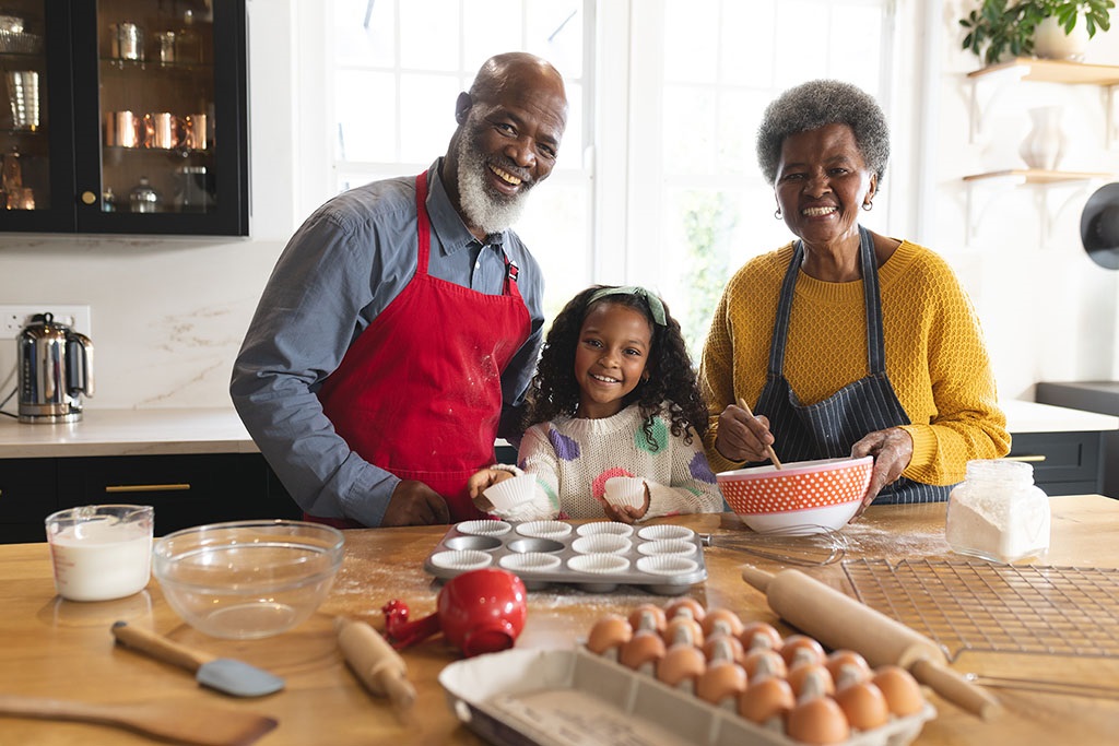 Grandparents and a child smiling as they bake