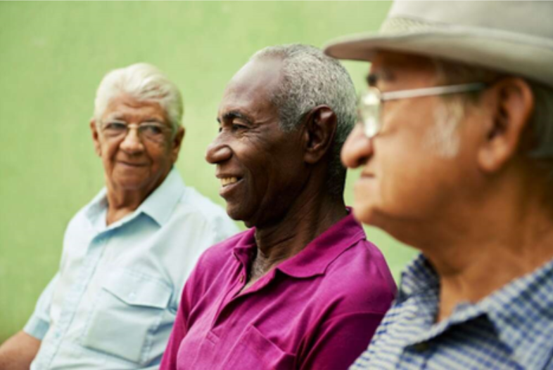 Three men sitting with a green lawn in the background.