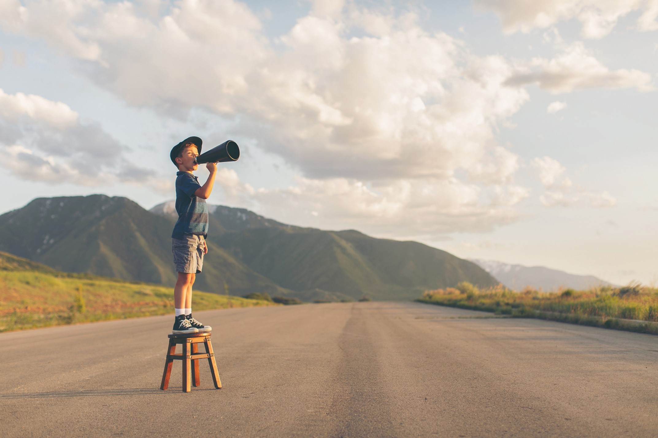 Photo of a child standing on a stool outside. 