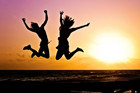 People jumping in front of a beach sunset