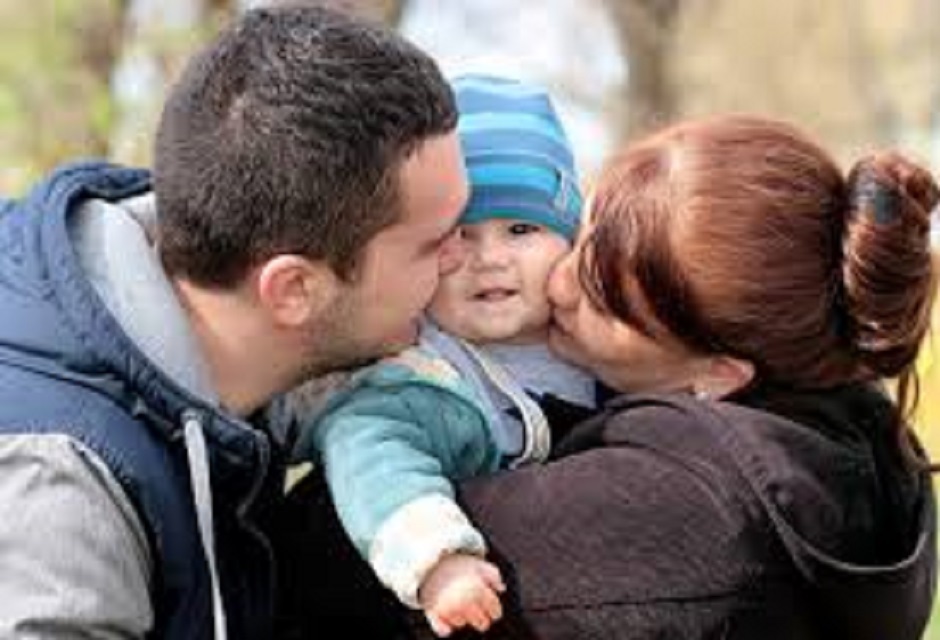 Parents holdiing a smiling baby in a blue striped beanie