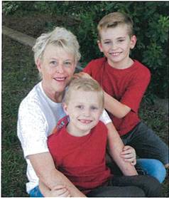 Grandmother sitting and smiling with two granchildren.