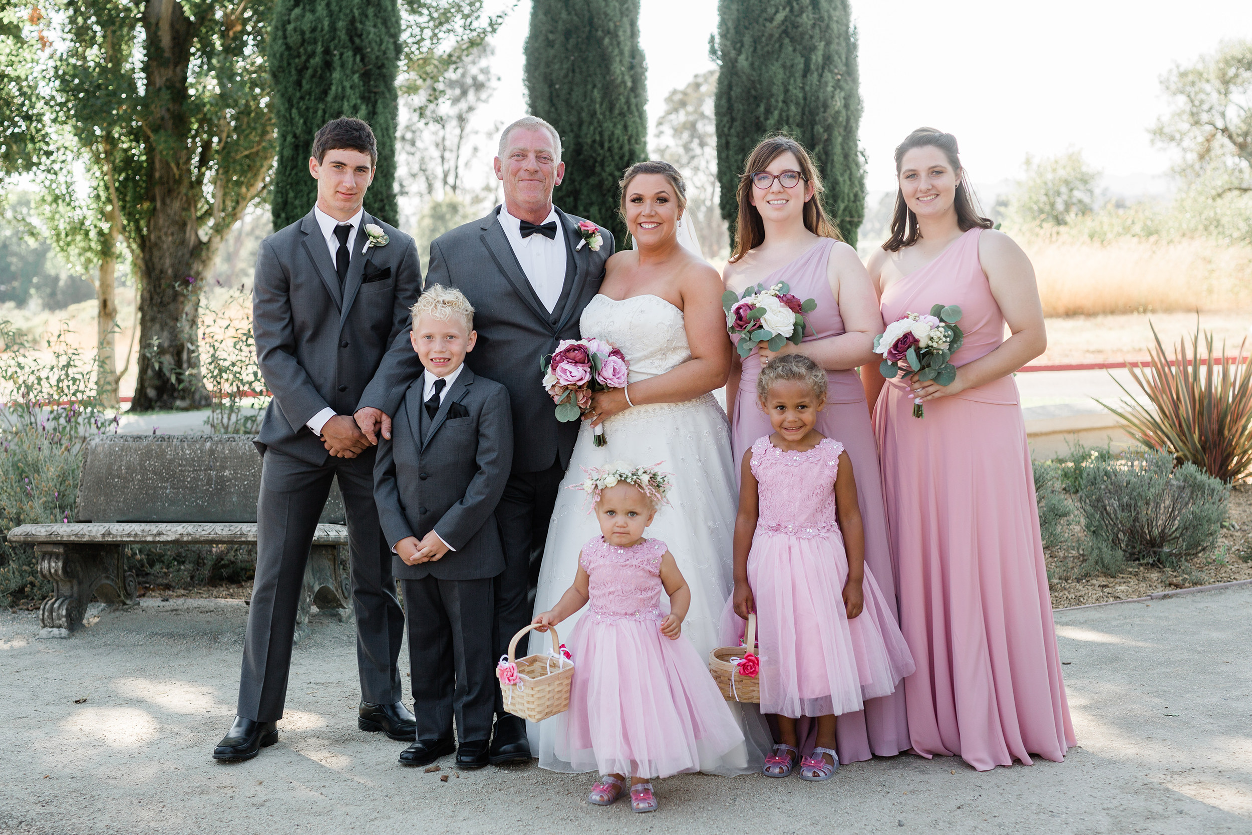 Family in wedding clothing standing in a garden