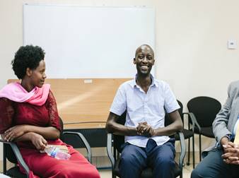 Photo of Ndizeye sitting and smiling in a room with others